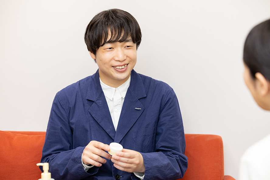 Ozawa being interviewed with a smile while facing Aoki.