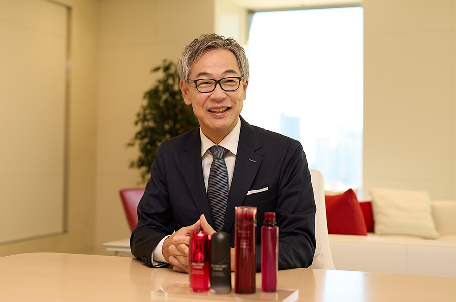 正面を向いて座り、アルティミューンとオイデルミンを前に、和やかな雰囲気でインタビューに答える資生堂社長CEOの藤原憲太郎の画像