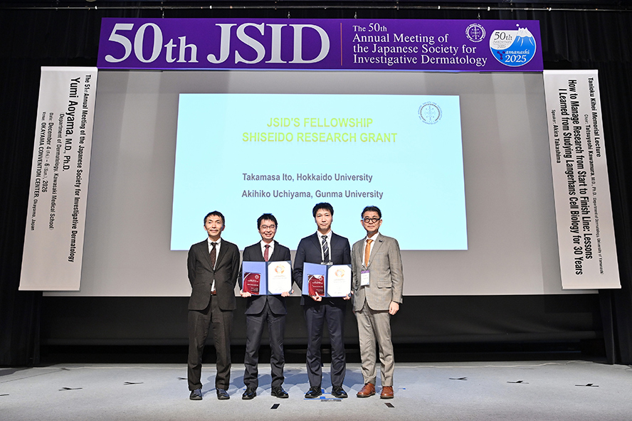 授与式会場で撮影された受賞者2名と事務局長の大山先生、資生堂みらい研究所 加治屋。